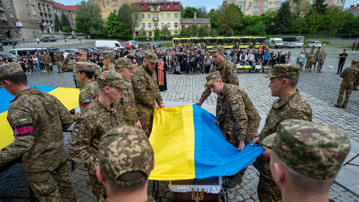 LVIV, UKRAINE - MAY 2: Soldiers of the honor guard cover the coffin with the body of a fallen soldier with the ceremonial Ukrainian flag of Ukraine during the farewell ceremony at the Lychakiv cemetery on May 2, 2024 in Lviv, Ukraine. A farewell ceremony for three Ukrainian servicemen has been held in Lviv. Taras Osmyakevych, Hennadiy Paliyevets and Oleksandr Holubkov died while defending Ukraine from the Russian army in late April. (Photo by Stanislav Ivanov/Global Images Ukraine via Getty Images)