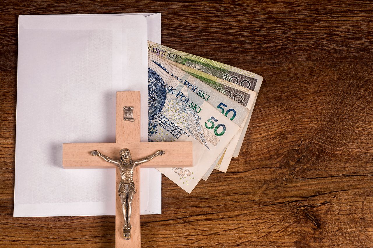 A crucifix lying on an envelope with Polish banknotes in the background