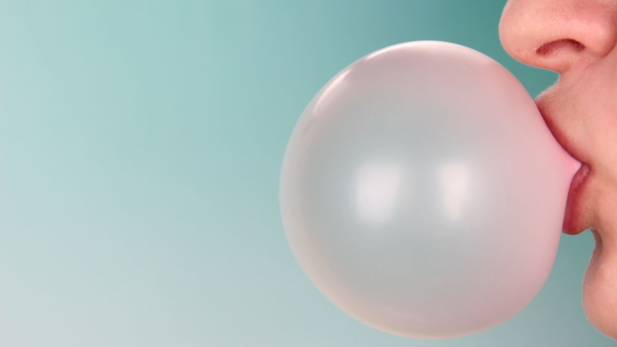 Person doing bubble with chewing gum on bright background
