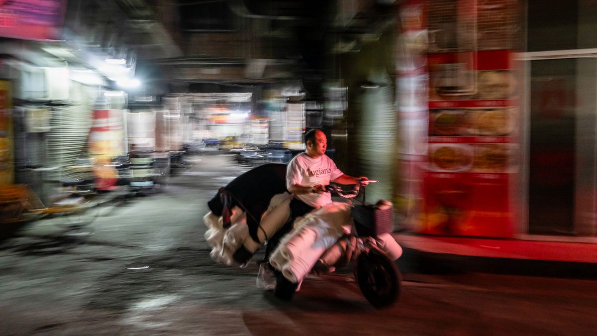 A motorcyclist transports rolls of fabric at night in the Datang district of Guangzhou, China, on Friday, Feb. 27, 2026. President Xi Jinping's increasingly powerful export machine stunned the world last year by generating a record $1.2 trillion trade surplus even after US counterpart Donald Trump raised American tariffs to the highest in nearly a century. Photographer: Qilai Shen/Bloomberg via Getty Images