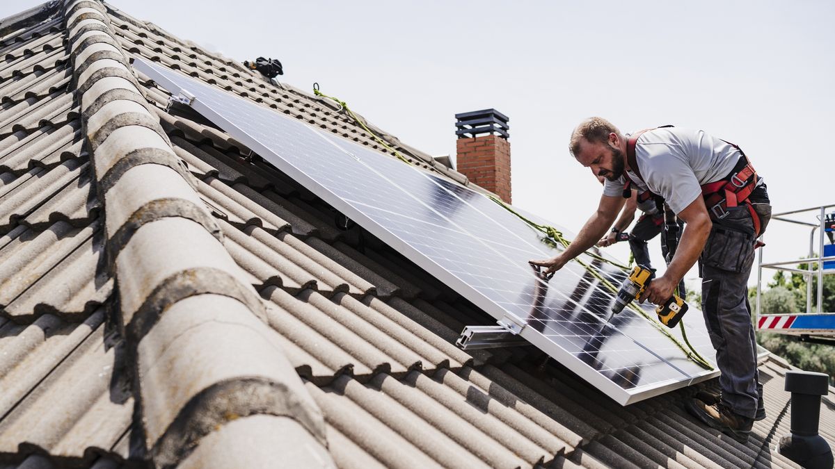 Electricians installing solar panels on rooftop of house
Westend61