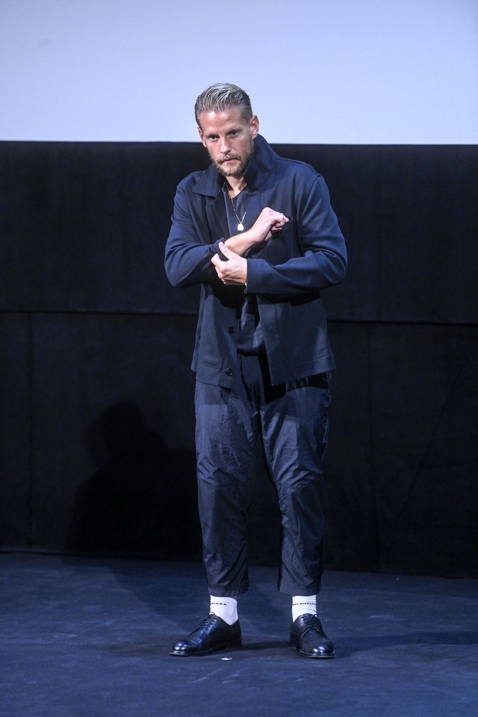 47. FPFF w Gdyni - wtorek, buty czarne, buty sznurowane, kurtka granatowa, kurtka sportowa, naszyjnik srebrny, scena, spodnie dresowe, spodnie granatowe, sylwetka, zarost, festiwal filmowy, festiwal w Gdyni, Festiwal Filmowy w Gdyni, festiwal filmowy w Gdyni 2022, Festiwal Polskich Filmów Fabularnych, Teatr Muzyczny, Teatr Muzyczny w Gdyni, Teatr Muzyczny im. Danuty Baduszkowej
