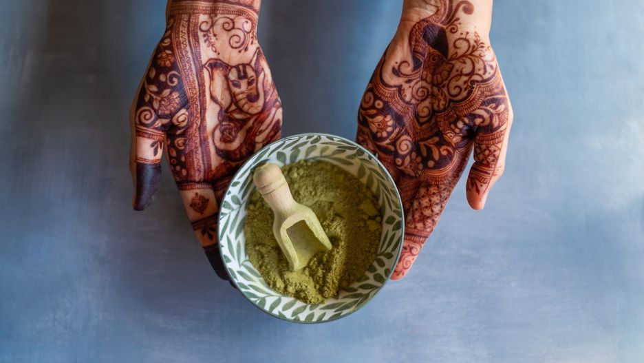 Woman showing henna tattoo and powder in a bowl