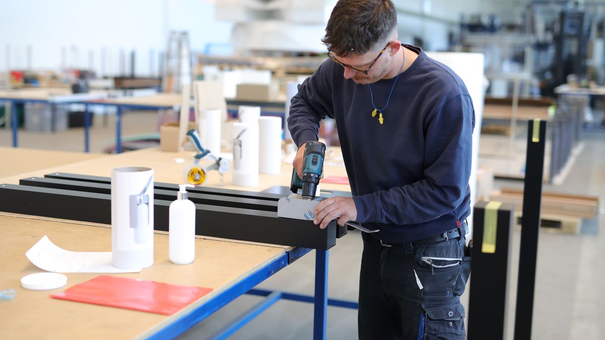 RHEINBREITBACH, GERMANY - MAY 18: Employee Daniel works on an elbow dispenser at Picos Grafik manufacture during the coronavirus crisis on May 18, 2020 in Rheinbreitbach, Germany. Demand for plexiglass has skyrocketed due to its use as a protective barrier during the pandemic, especially in retail stores to stop the spread of the virus from customers to employees. Picos Grafik, which in normal times manufactures exhibitor stands for trade fairs and fashion weeks, has seen upcoming trade fairs cancelled due to the pandemic and has ordered enough plexiglass material early to produce protective plexiglass panels, spit panels, elbow dispensers, etc. to guarantee orders can be made within three working days and delivered. Due to the high demand, a waiting time of 14 weeks can be expected for acrylic glass blanks in Germany.   (Photo by Andreas Rentz/Getty Images)
