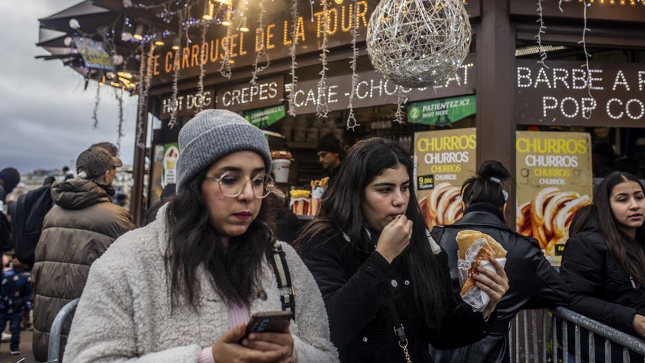 PARIS, FRANCE - DECEMBER 25: People gather around food shop of crepes and churros around the Tour Eiffel as they celebrate Christmas ahead of the New Year's eve in Paris, France on December 25, 2023. (Photo by Bruno Thevenin/Anadolu via Getty Images)