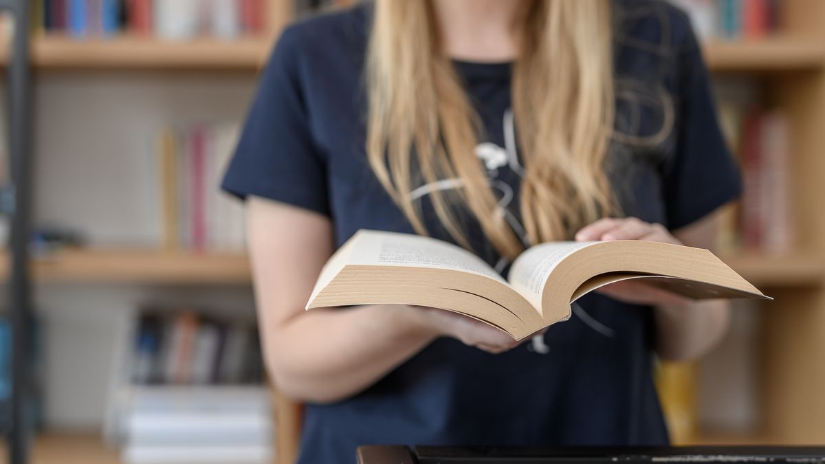 Kobieta przeglądająca książki w bibliotece, lektury szkolne
