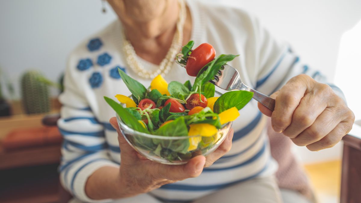 Starsza kobieta je sałatkę.