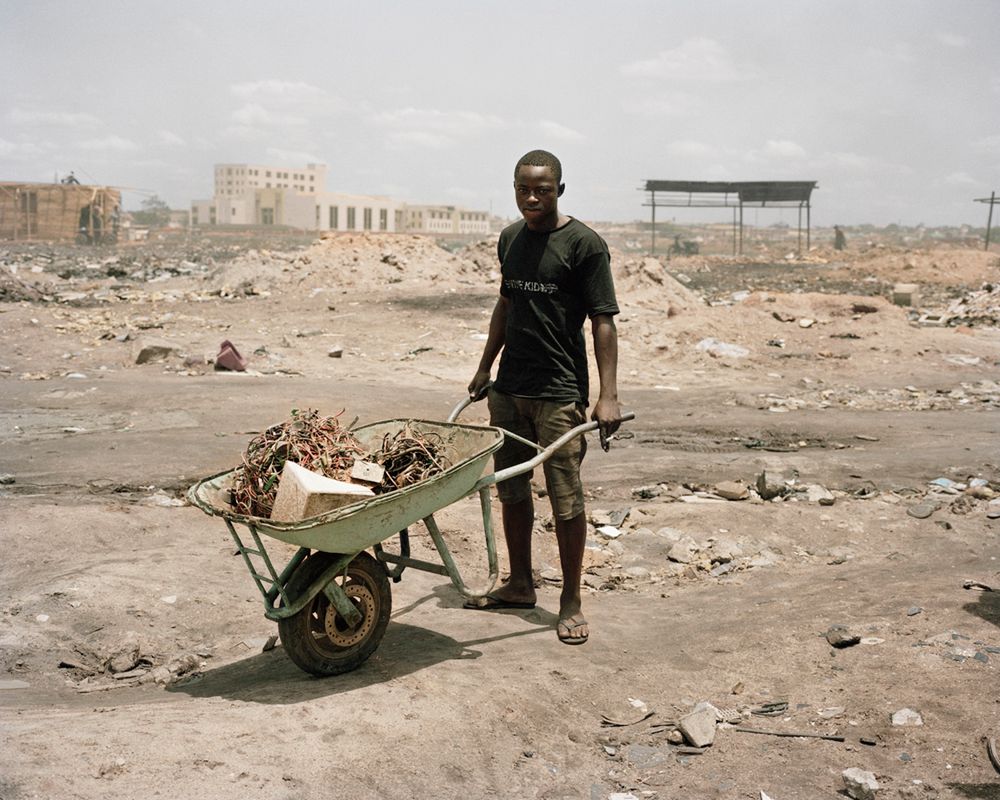 Agbobloshie, Accra, Gana: Młody mężczyzna przewozi materiały elektroniczne do spalenia. Przetwarzane materiały zawierają substancje, które są bardzo toksyczne dla środowiska i człowieka.