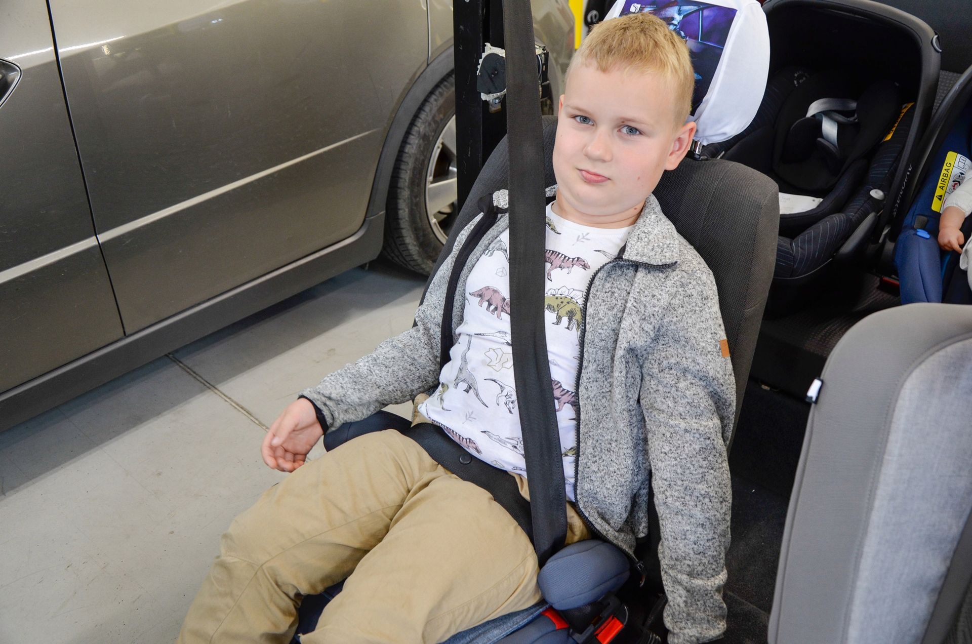Lepiej - czyli dziecko na podwyższeniu zapiętym w Isofix. Pas biodrowy jest prowadzony prawidłowo, po udach, ale ramieniowy pozostaje luźny.