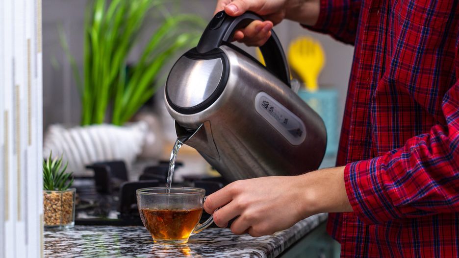 A person makes tea using boiling water from an electric kettle in kitchen at home. Time for breakfastkettle, brew tea, electric kettle, make tea, teapot, kitchen, electric, tea, appliance, coffee, metal, pot, beverage, drink, hot, domestic, water, steel, utensil, electricity, equipment, handle, stainless, electrical, home, boiler, boil, preparation, household, kitchenware, heat, breakfast, pouring, cup, preparing, teakettle, device, reflection, boiling, switch, technology, steam, thermal, cooking, teatime, making tea, brewed, brewed tea, hot tea, cup tea, boiling water
