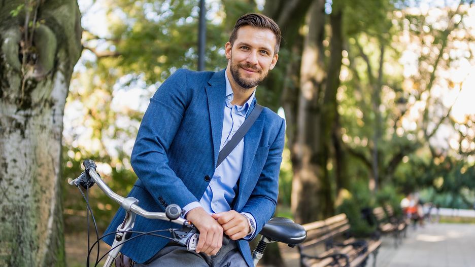  Uśmiechnięty mężczyzna na rowerze w parku - tytułowa
