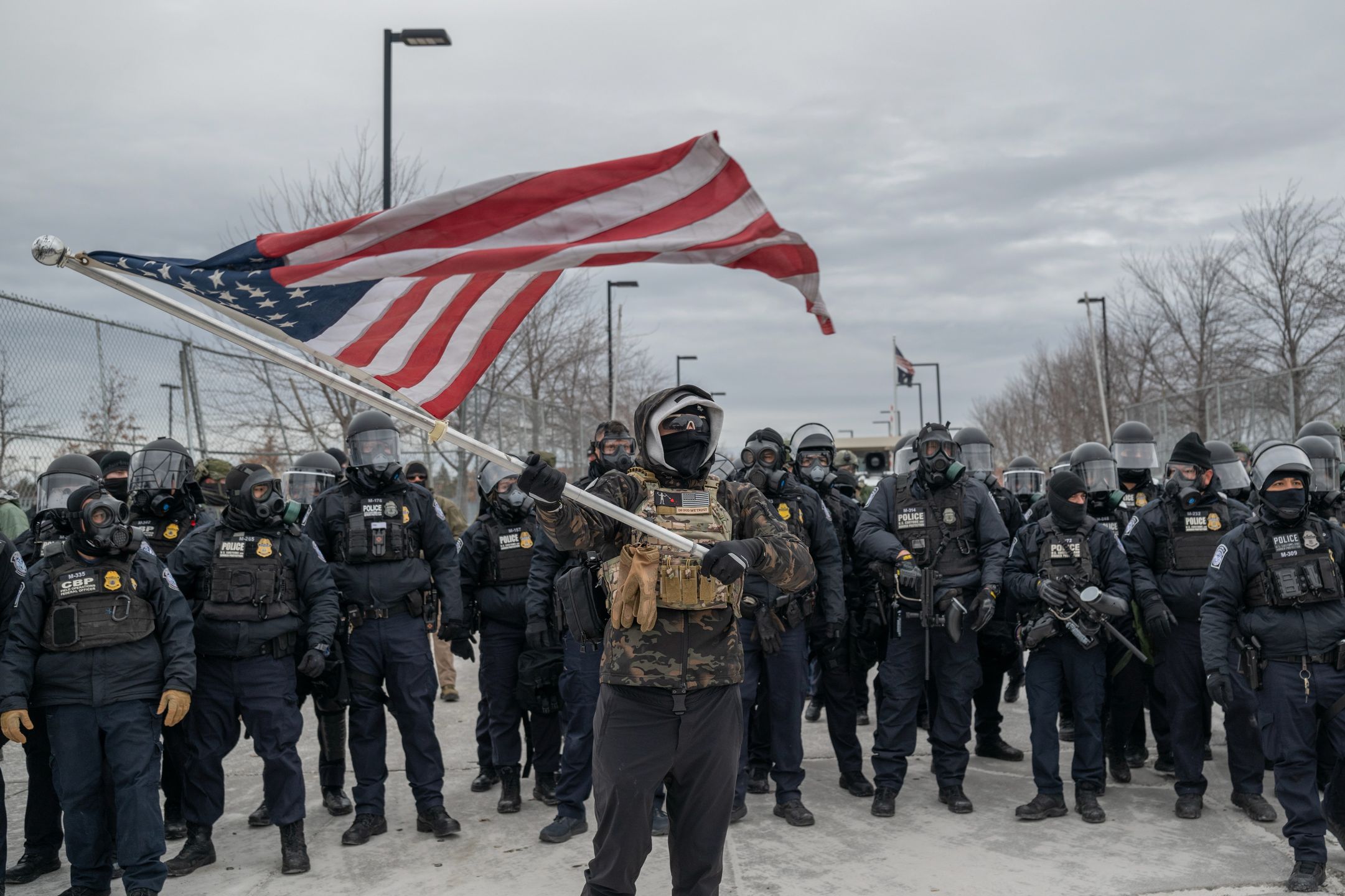 Trump Threatens Insurrection Act As Minnesota Protests GrowA demonstrator waves a US flag in front of federal law enforcement officers outside the Bishop Henry Whipple Federal Building in St. Paul, Minnesota, US, on Thursday, Jan. 15, 2026. President Donald Trump threatened to deploy US military forces to Minnesota in order to quell protests in response to violent encounters involving federal immigration agents. Photographer: Victor J. Blue/Bloomberg via Getty ImagesBloomber