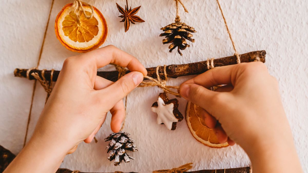 Kobieta wiesza ozdoby na choince z patyków