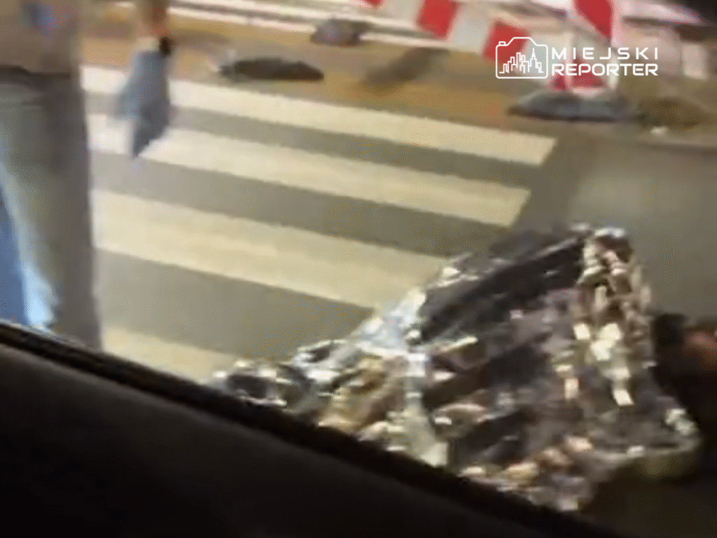 Mężczyzna w rękawiczkach podnosi folię termiczną z jezdni na przejściu dla pieszych.