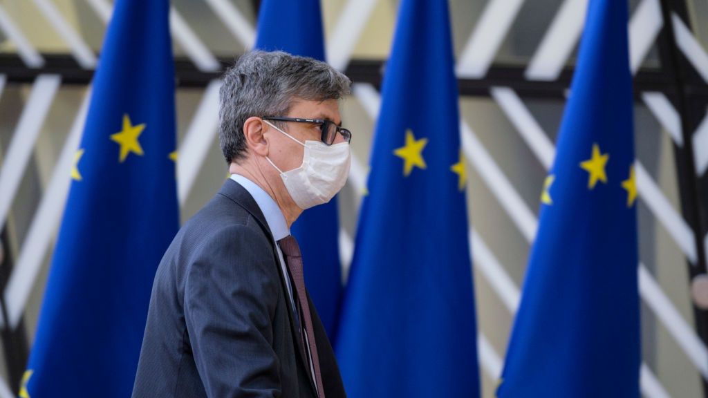 Na zdjęciu Virgil Popescu w maseczce na tle flag UE