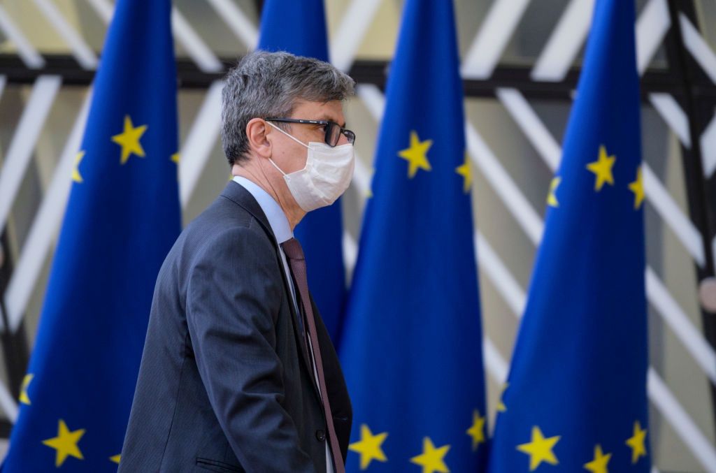 Na zdjęciu Virgil Popescu w maseczce na tle flag UE