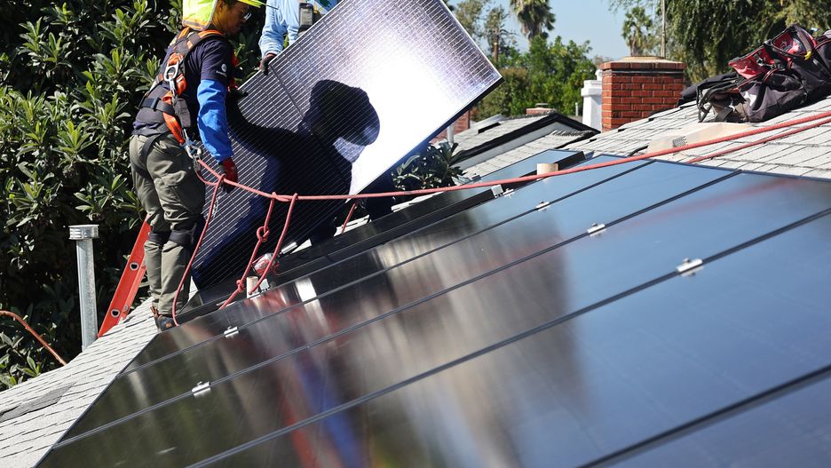 POMONA, CALIFORNIA - OCTOBER 19: GRID Alternatives employee Tony Chang (L) installs no-cost solar panels on the rooftop of a low-income household on October 19, 2023 in Pomona, California. GRID Alternatives has installed no-cost solar for over 29,000 low-income households located in underserved communities which are most impacted by pollution, underemployment and climate change. They are the country’s biggest nonprofit clean energy technologies installer and operate in California, mid-Atlantic states and Colorado. (Photo by Mario Tama/Getty Images)