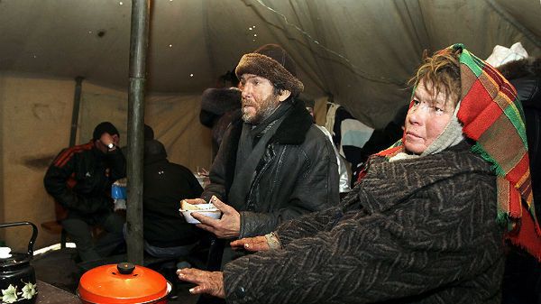 Bezdomni ogrzewają się w namiocie z gorącą herbatą i żywnością, który został wybudowany przez ukraińskich ratowników w Doniecku