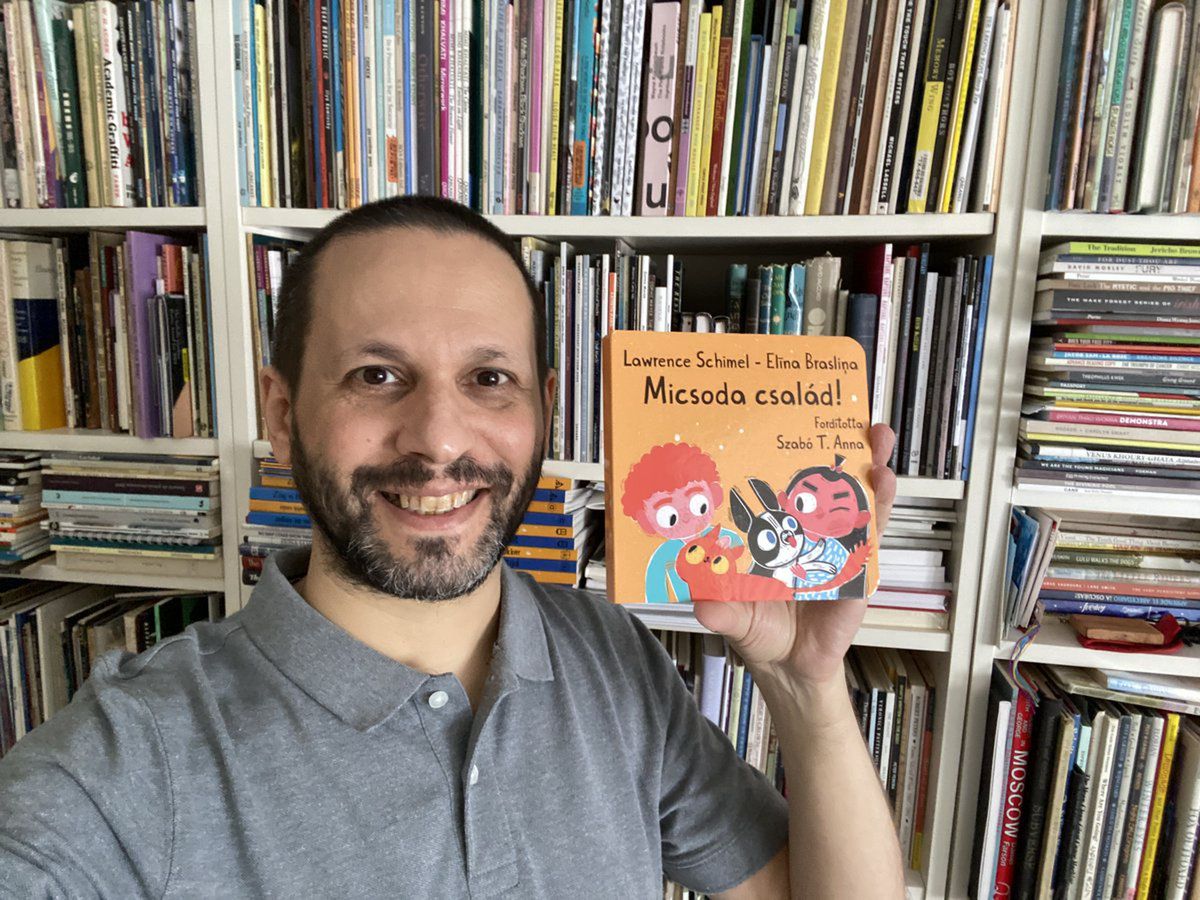 Lawrence Schimel trzyma w ręku węgierskie wydanie swojej książki dla dzieci o "tęczowej rodzinie".