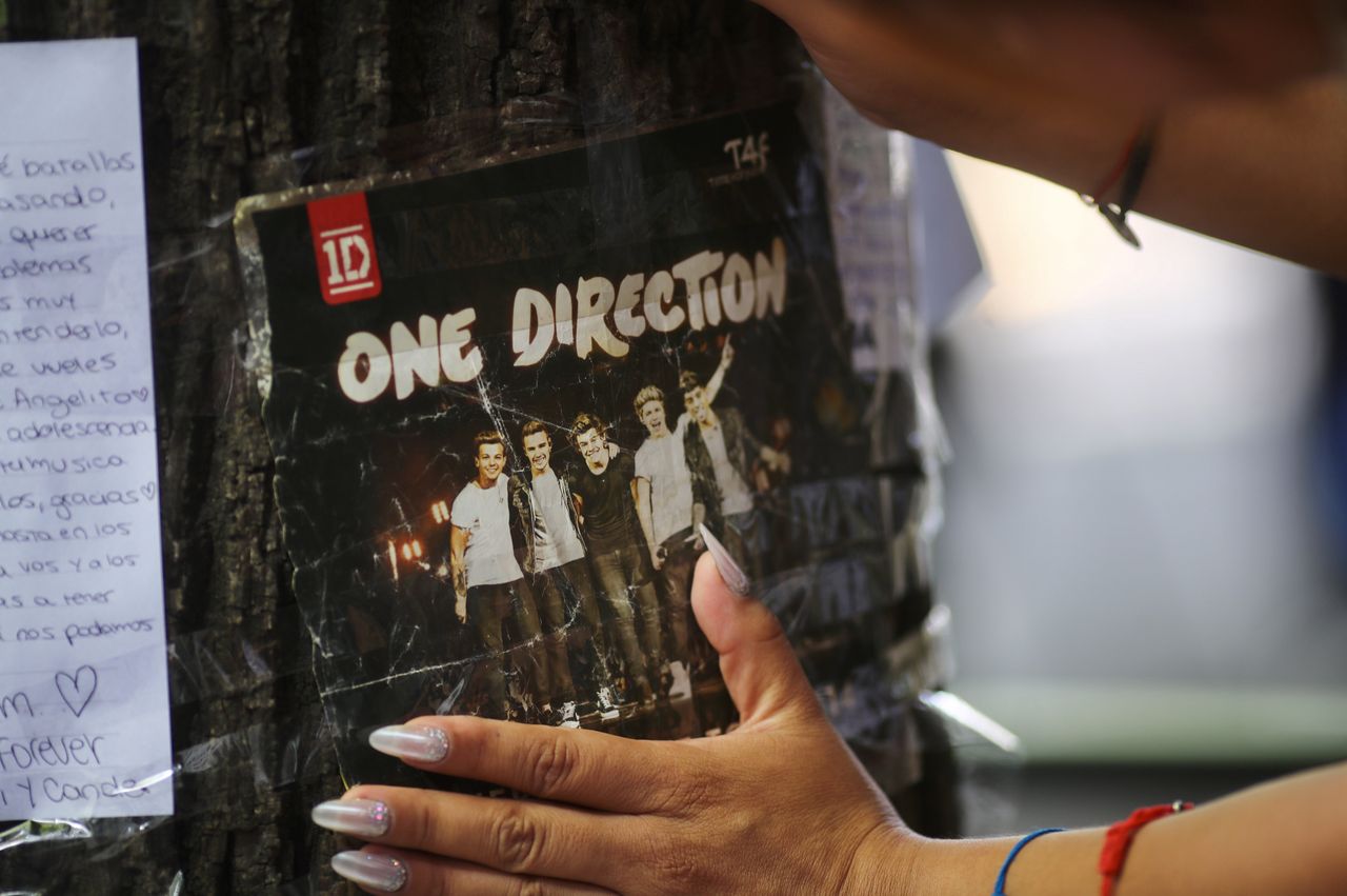 BUENOS AIRES, ARGENTINA - OCTOBER 17: A woman places a picture of One Direction on a tree outside Casa Sur Hotel on October 17, 2024 in Buenos Aires, Argentina. According to the Buenos Aires police department, Payne fell from a third-floor hotel room balcony in Palermo, a famous neighborhood in Buenos Aires. Fans around the city gather to pay tribute to the former member of boy band One Direction. (Photo by Marcos Brindicci/Getty Images)