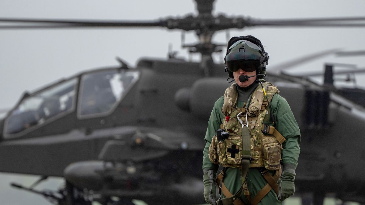IPSWICH, ENGLAND - APRIL 23: A pilot waits by a Wildcat helicopter as a fleet of more than a dozen Apache, Wildcat and Chinook helicopters assemble to take-off together from Wattisham Flying Station in Suffolk for training in Finland and Estonia on Exercise Steadfast Defender 24, on April 23, 2024 in Ipswich, England. On their first NATO deployment, the new Apache variant will take part in Exercise Arrow in Finland, flying strike missions in support of large-scale Finnish Army training. All three helicopter types will be operating together in Estonia under the command of 16 Air Assault Brigade Combat Team, the British Army's global response force. Photo by Carl Court/Getty Images)