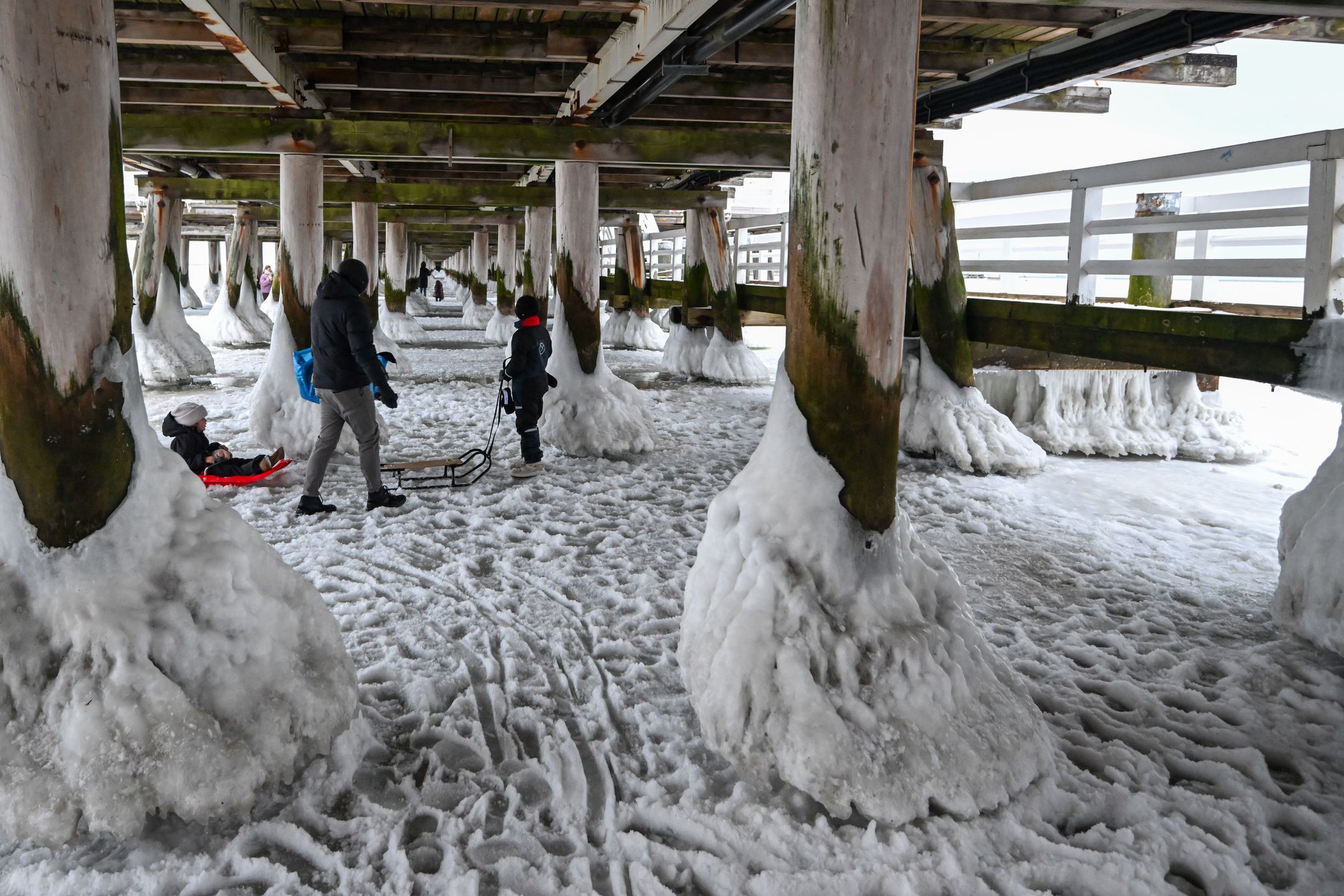 Sopot, 08.02.2026. Skuty lodem Bałtyk w Sopocie, 8 bm. Morze Bałtyckie zamarzło przy linii brzegowej. Mimo ostrzeżeń straży miejskiej, mieszkańcy i turyści spacerują po lodowej tafli. (aldg) PAP/Andrzej Jackowski