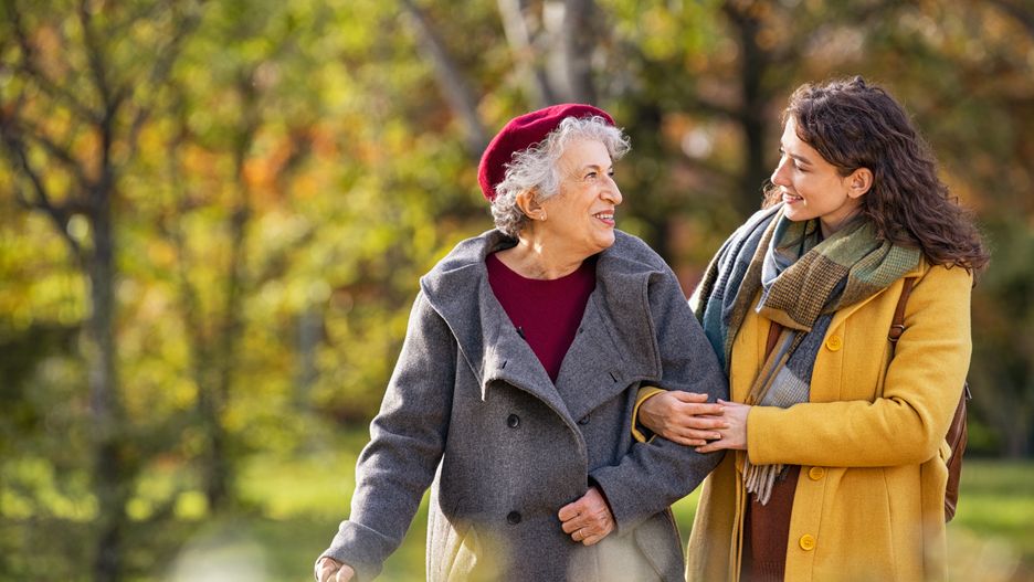 Young woman in park wearing winter clothing walking with old grandmother. Happy grandma wearing coat walking with lovely girl outdoor with copy space. Smiling lovely caregiver and senior lady walking in park during autumn and looking at each other.francescoridolfi.comsenior, woman, grandmother, granddaughter, walking, caregiver, old, outdoor, talking, talk, love, happy, carefree, smile, smiling, care, together, help, helping, lovely, walk, girl, elder, elderly, nursing, autumn, grandma, winter, assistance, daughter, disability, disabled, embrace, enjoying, joy, enjoy, family, mother, nature, park, people, young, aged, fall, copy space, embracing, support, aging