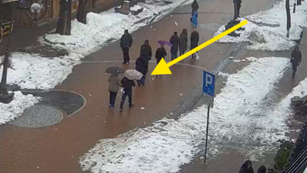 Turyści używają parasolek na Krupówkach.