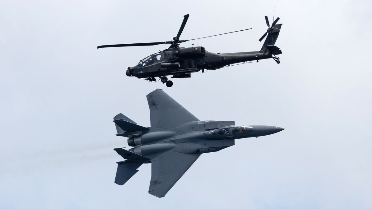 A Republic of Singapore Air Force (RSAF) F-15 SG fighter jet, manufactured by Boeing Co., bottom, and a Boeing AH-64D Apache helicopter during an aerobatic flying display at the Singapore Airshow in Singapore, on Tuesday, Feb. 20, 2024. Aircraft delivery delays, the uphill battle of going green by 2050 and elevated airfares that increasingly make flying the domain of the wealthy  all these topics and more will be in focus this week as executives from over 1,000 companies descend on Singapore for Asia's most influential aerospace and defense exhibition. Photographer: SeongJoon Cho/Bloomberg via Getty Images