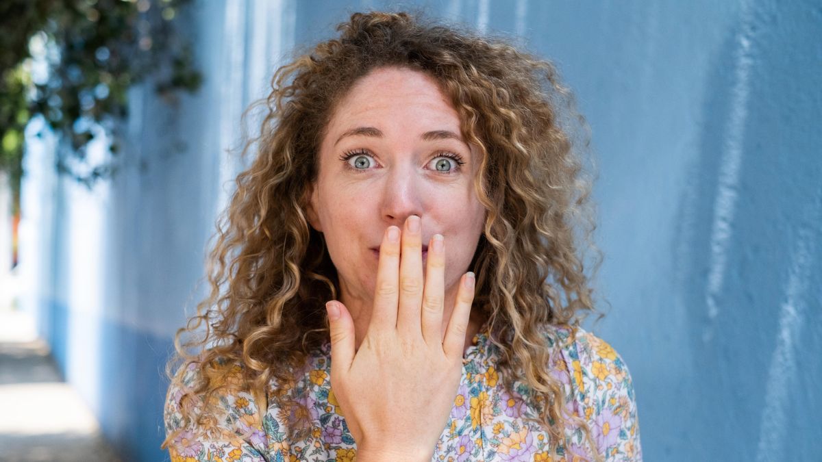 Kobieta zasłania dłonią usta
