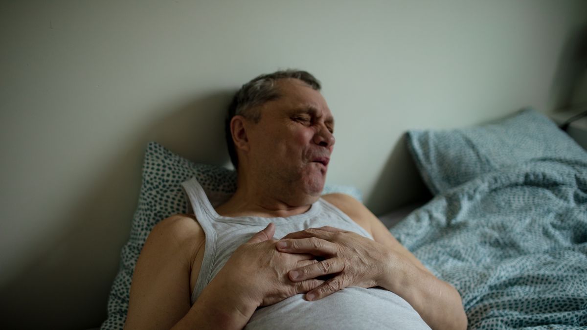 Senior man in white sleeveless t-shirt lying in bed suffering pain in chest.
Senior man lying in bed, wearing white sleeveless t-shirt, holding hands on chest and grimacing with eyes closed because person suffering pain in chest related to heart problems.
Tatsiana Volkava