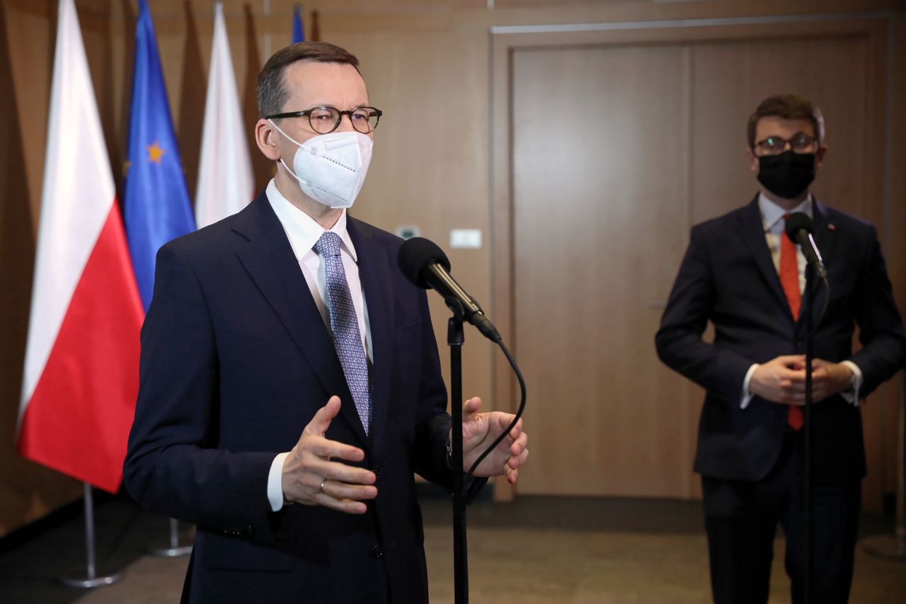 Premier Mateusz Morawiecki podczas konferencji prasowej na Okęciu (w tle rzecznik rządu Piotr Mueller)