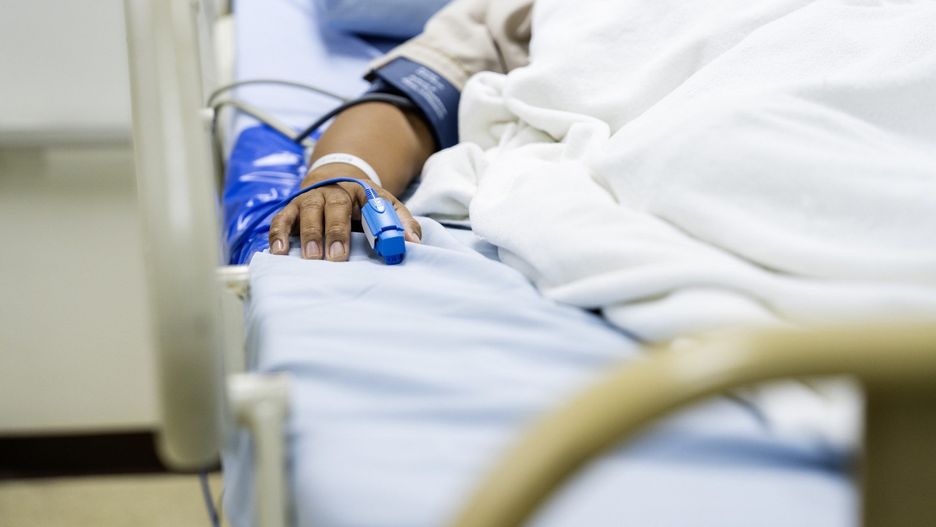 In the Hospital Sick Male Patient Sleeps on the Bed. Heart Rate Monitor Equipment is on His Finger.