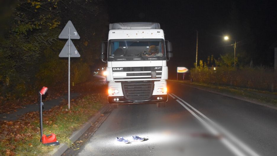 Ciężarówka DAF zatrzymana na drodze nocą, obok leżące niebieskie buty na oświetlonym asfalcie.