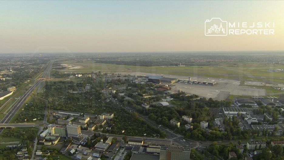 Widok z lotu ptaka na nowoczesne lotnisko z pasami startowymi i terminalami, otoczone terenami zielonymi oraz miejską zabudową.