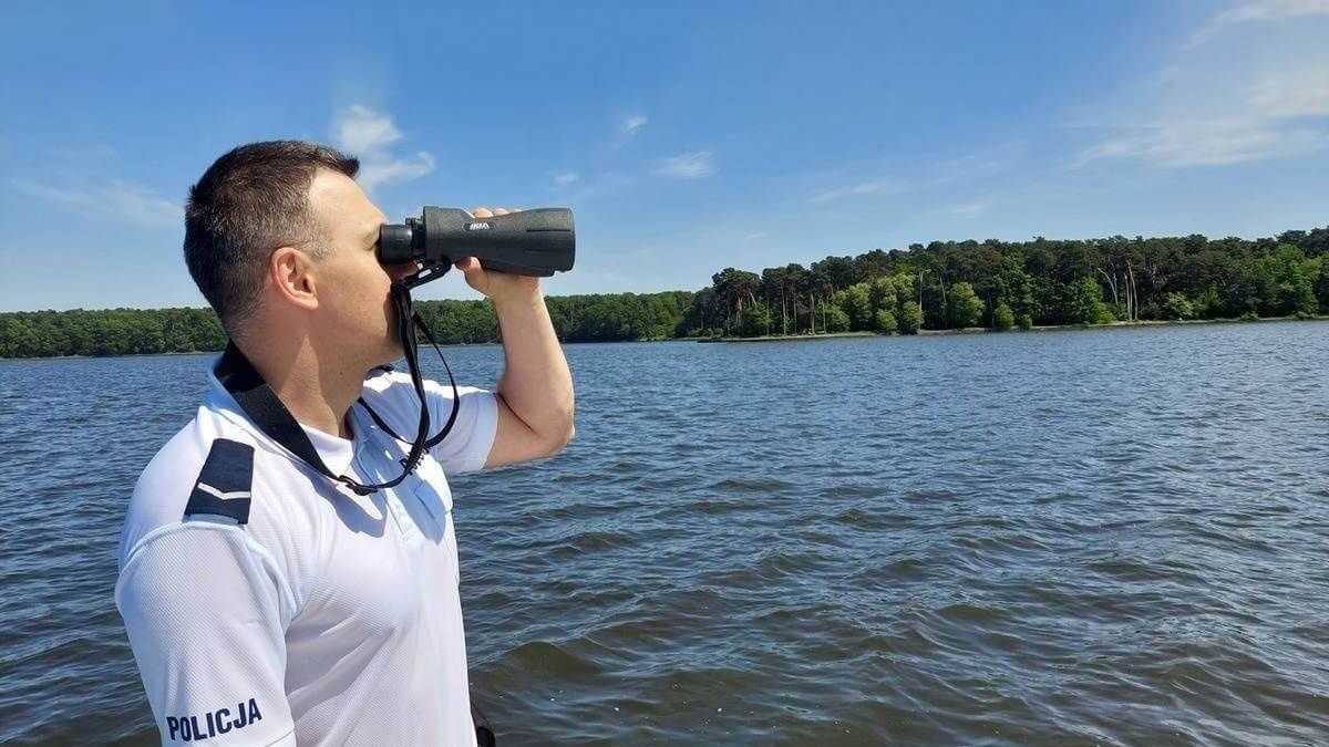 Policjant z lornetką obserwuje wodę