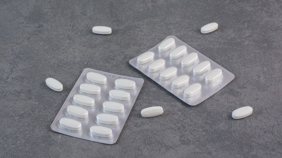 Two packs of white pills on marble background