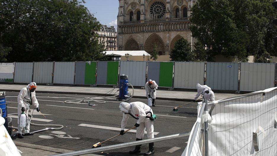 Pracownicy oczyszczają płynnymi chemikaliami teren przed Notre Dame pierwszego dnia po powrocie do pracy