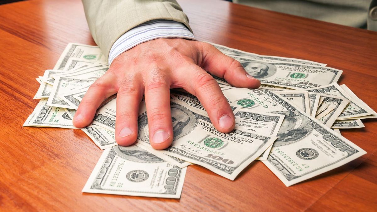 Zdjęcie przedstawia rękę trzymającą pieniądze - symbol chciwości 