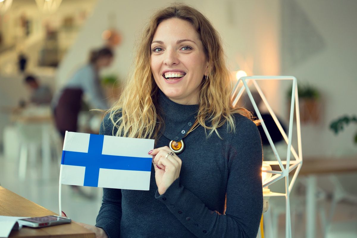 The smiling woman holds the Finnish flag.