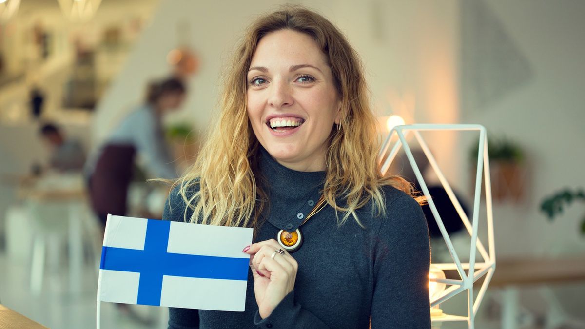 Uśmiechnięta kobieta trzyma fińską flagę