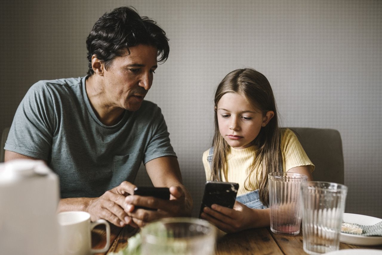 Ojciec przegląda z córką smartfona
