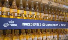 Butelki piwa Corona w kampanii ustawione odwrotnie na półkach sklepowych