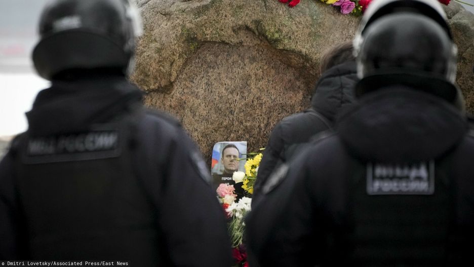 Policjanci przyglądają się, jak ludzie składają kwiaty, by oddać ostatni hołd Aleksiejowi Nawalnemu pod pomnikiem – dużym głazem z Wysp Sołowieckich