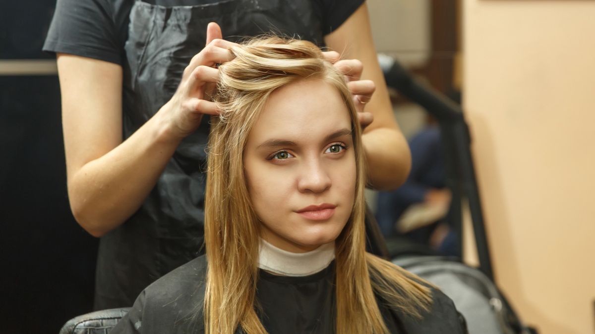 Professional hairdresser dyeing hair of her client in salon. Haircutter dry hair with hairdrier. Selective focusProfessional hairdresser dyeing hair of her client.licsiren