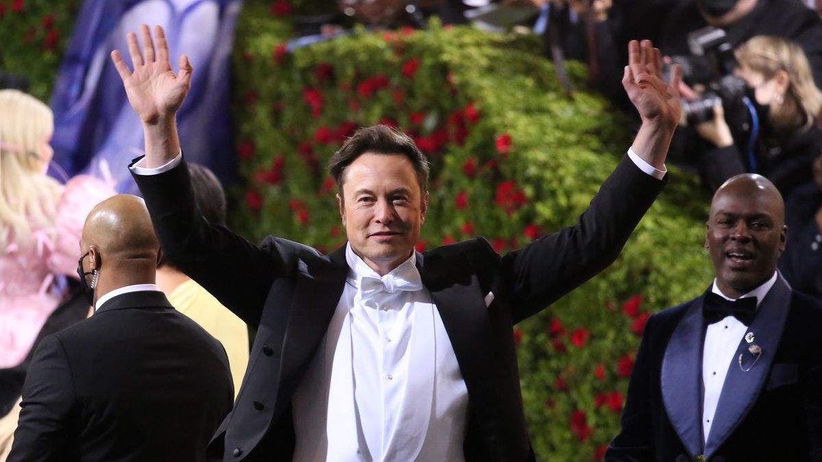 Na zdjęciu Elon Musk w smokingu unoszący ręce w górę