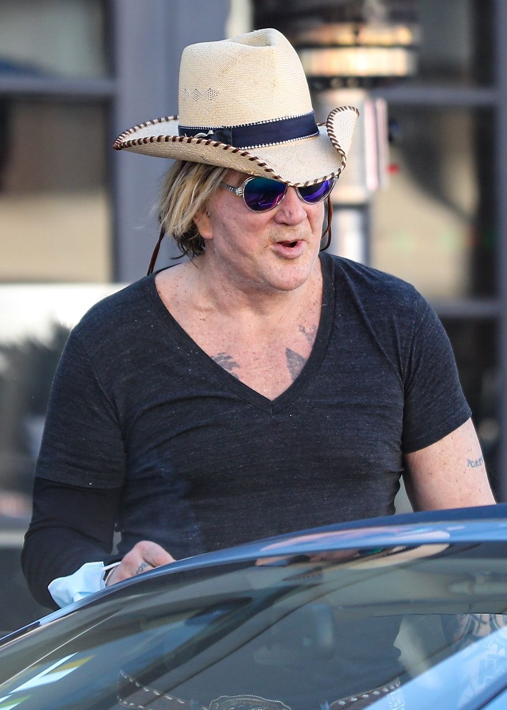 Zmarnowany Mickey Rourke wyłania się z samochodu w kowbojskim kapeluszu 