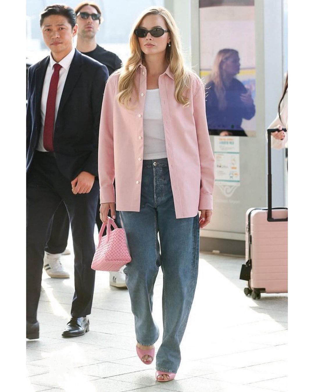 Margot Robbie w nonszalanckiej stylizacji z jeansami i różową koszulą