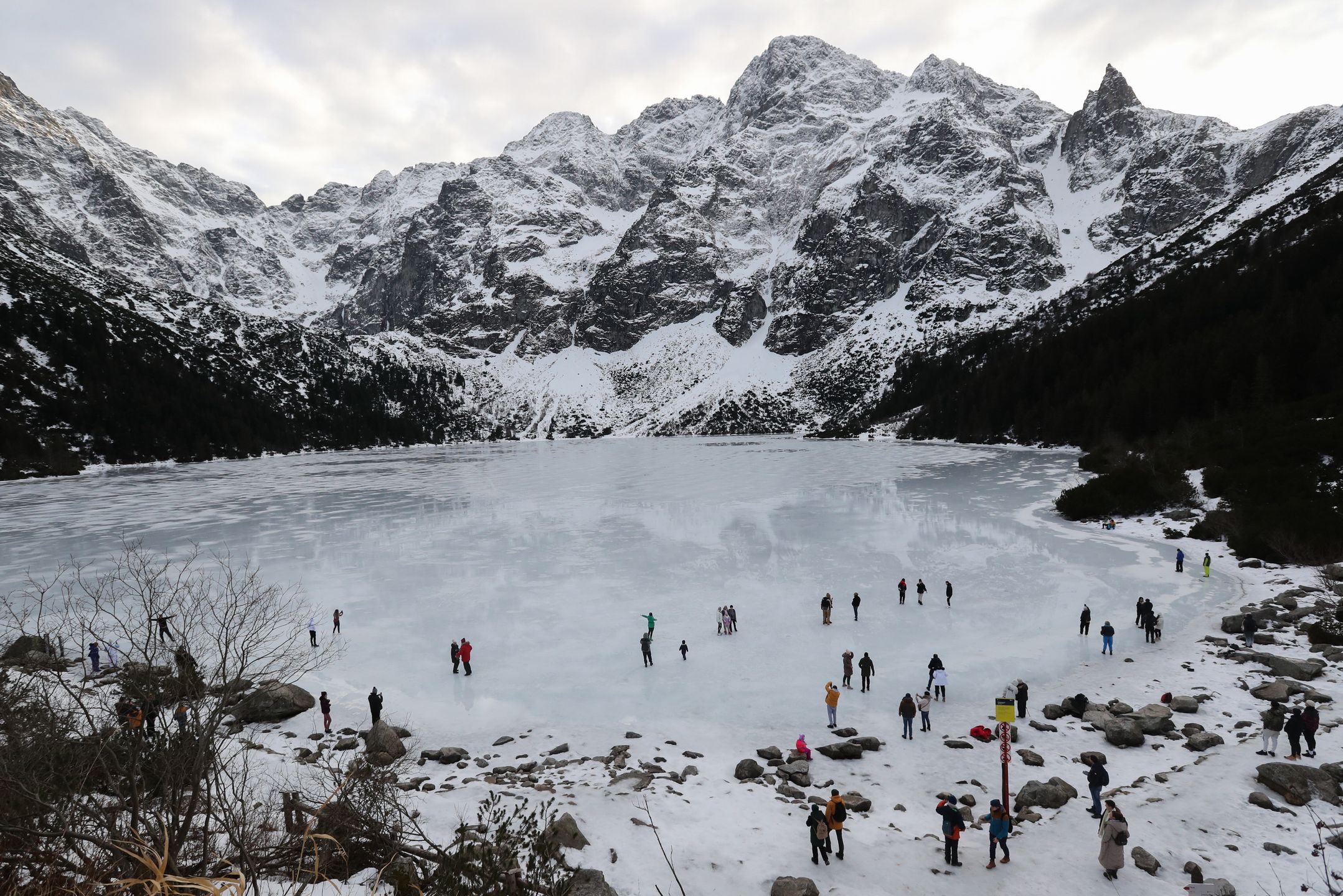 Tatry, Morskie Oko, 26.12.2022. Turyści na tafli lodu na jeziorze Morskie Oko w Tatrach, 26 bm. Tatrzański Park Narodowy ostrzega przed wchodzeniem na zamarznięte górskie jeziora � z powodu panujących w ciągu dnia dodatnich temperatur lód jest bardzo cienki i grozi załamaniem. (jm) PAP/Grzegorz Momot