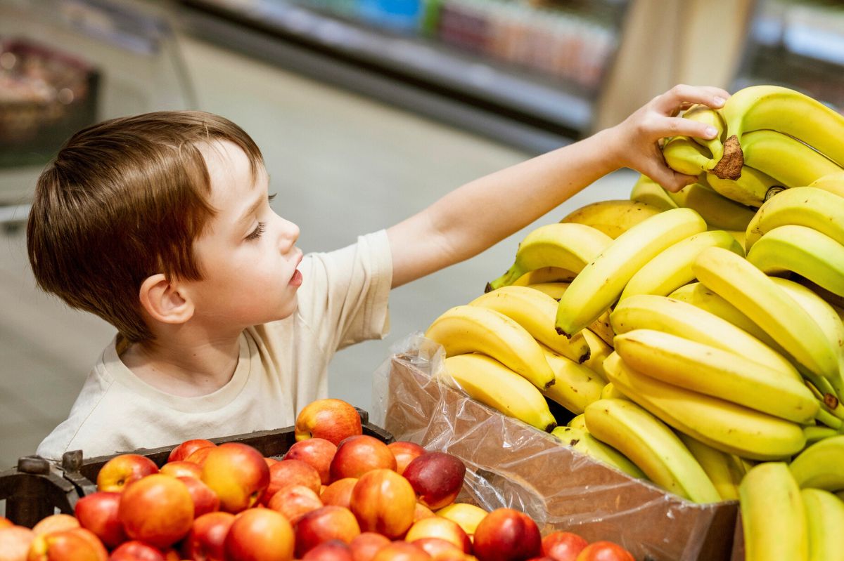 Dziecko bierze banany w sklepie
